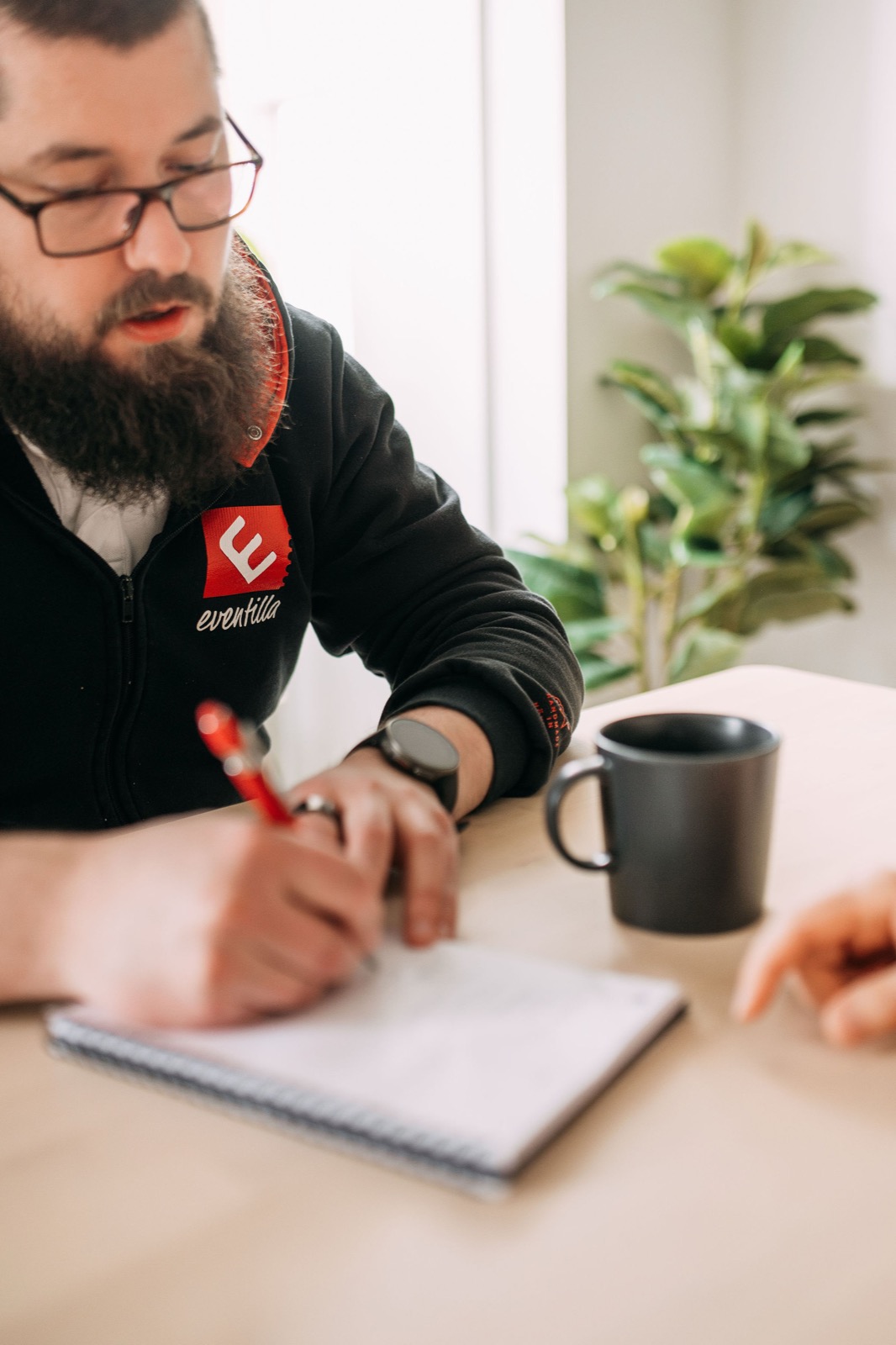 A CompetenceFlow team member writing notes by hand at a desk in the Oulu office in Finland
