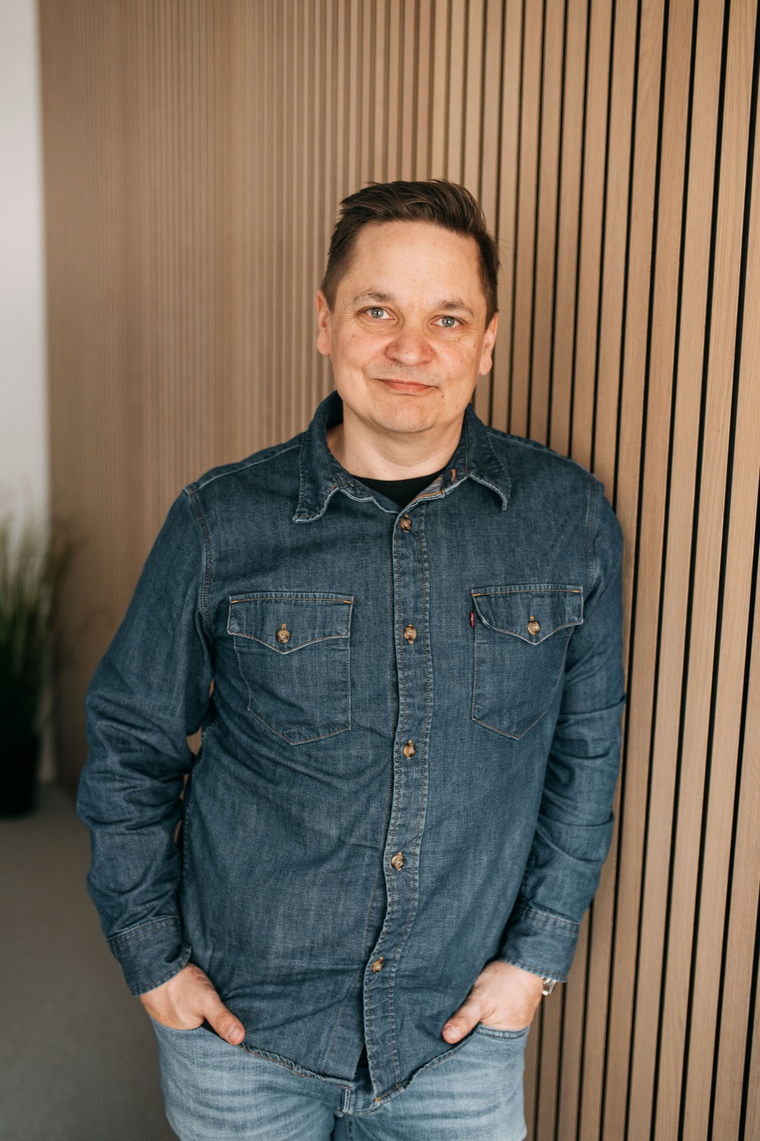 A CompetenceFlow team member standing against a wood-panelled wall in the Oulu office in Finland
